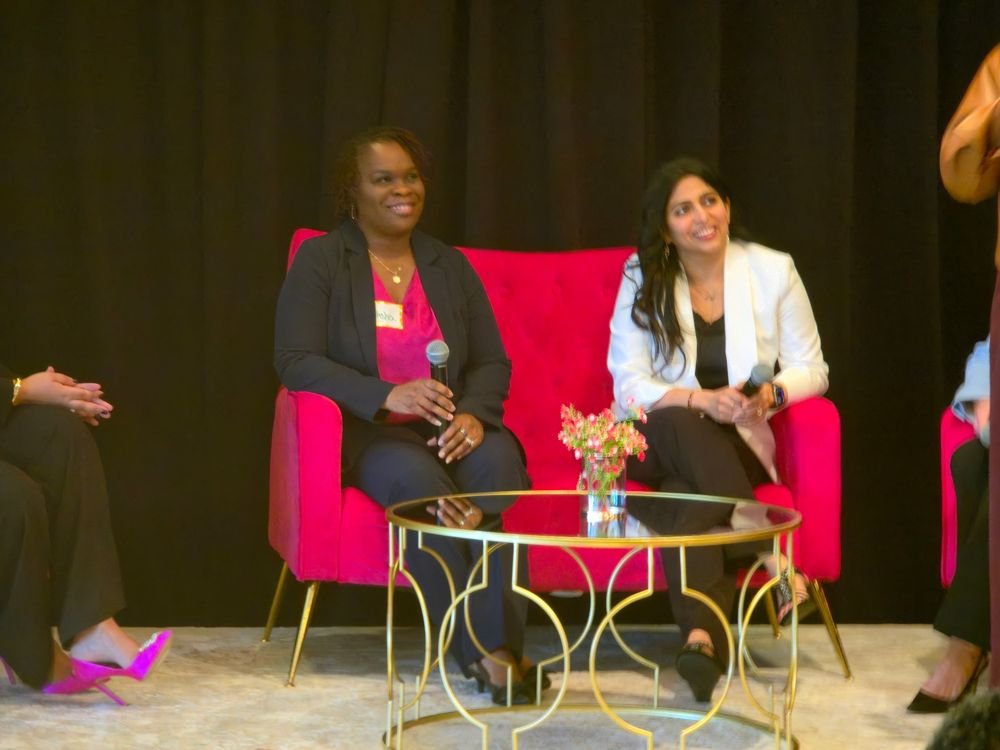 A panel conversation in armchairs on stage at a women’s leadership event.