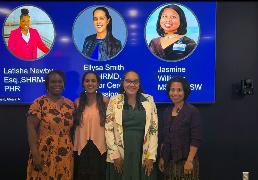 Four panelists standing together after a session, with the event slide behind them.
